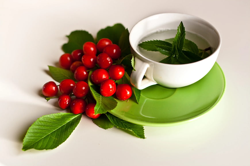 Fresh cherries and mint tea on a white background