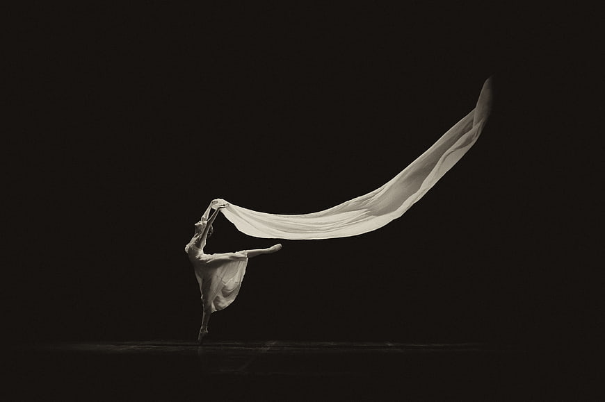 Ballerina with flowing fabric in dramatic black and white dance pose