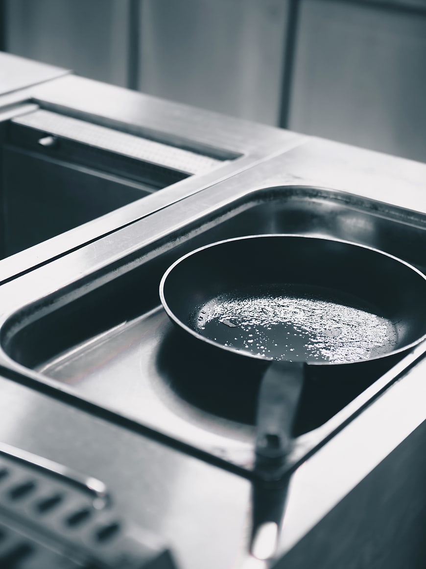 Close-up of frying pan with oil in commercial kitchen sink