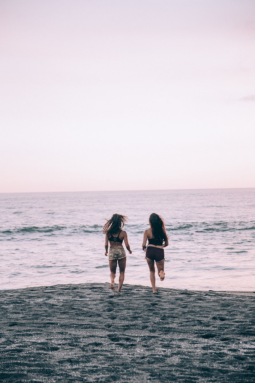 Two Women Running on Beach at Sunset