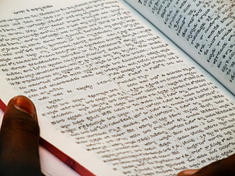 Close-up of hand holding open book with Telugu script