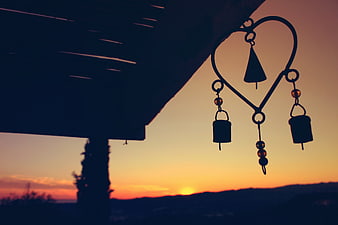 Heart-shaped wind chimes silhouette against sunset