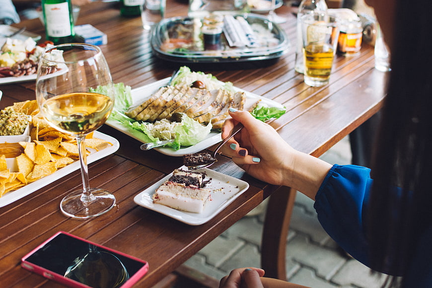 Woman eating cake and drinking wine at outdoor summer party
