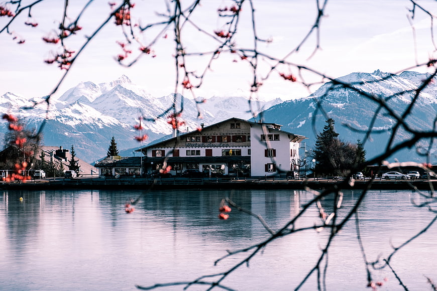 Lakeside hotel with snow-capped mountains and spring blossoms