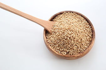 Sesame Seeds In Wooden Bowl With Spoon On White Background