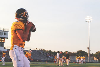 American Football Quarterback Throwing Ball at Sunset
