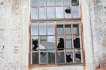 Broken window in abandoned building with rusted frame