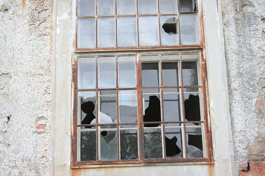 Broken window in abandoned building with rusted frame