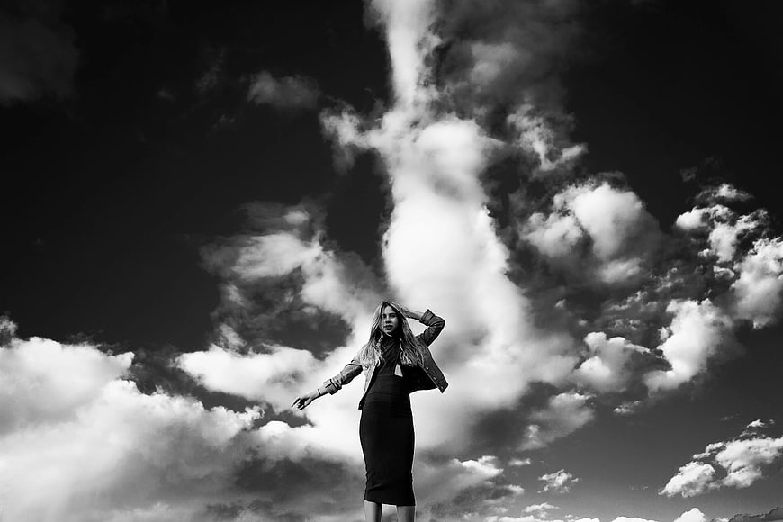 Dramatic Black and White Portrait of Woman Against Clouds