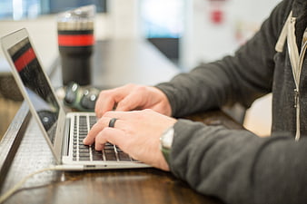Close-up of hands typing on a laptop keyboard at a desk