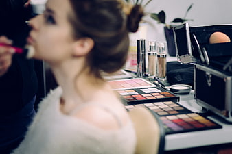 Woman Getting Makeup Applied with Cosmetics on Table