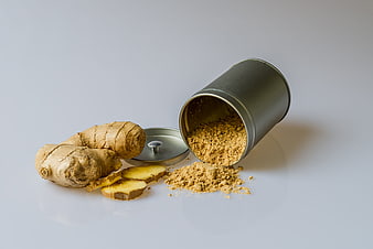 Fresh ginger root and powder spilling from tin can