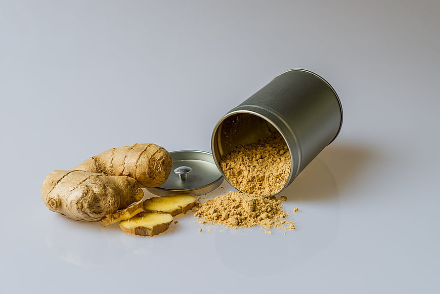 Fresh ginger root and powder spilling from tin can