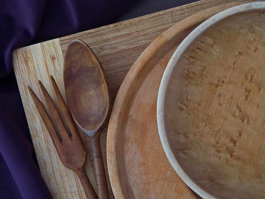 Handcrafted wooden bowl, spoon, and fork on a cutting board
