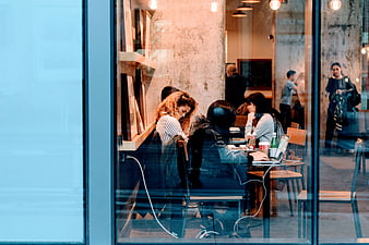 People working on laptops in a modern cafe seen through window