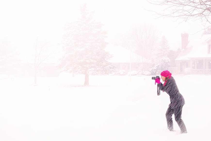 Woman photographer capturing snowstorm in winter landscape