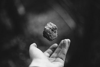 Black and white hand levitating a rock