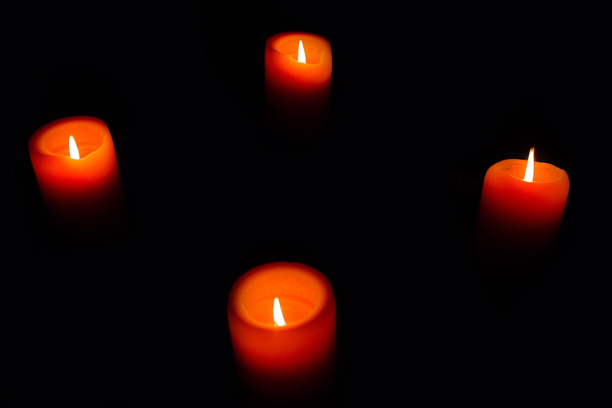 Four lit red candles glowing in the dark