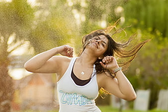 Woman dancing Zumba outdoors with water spray