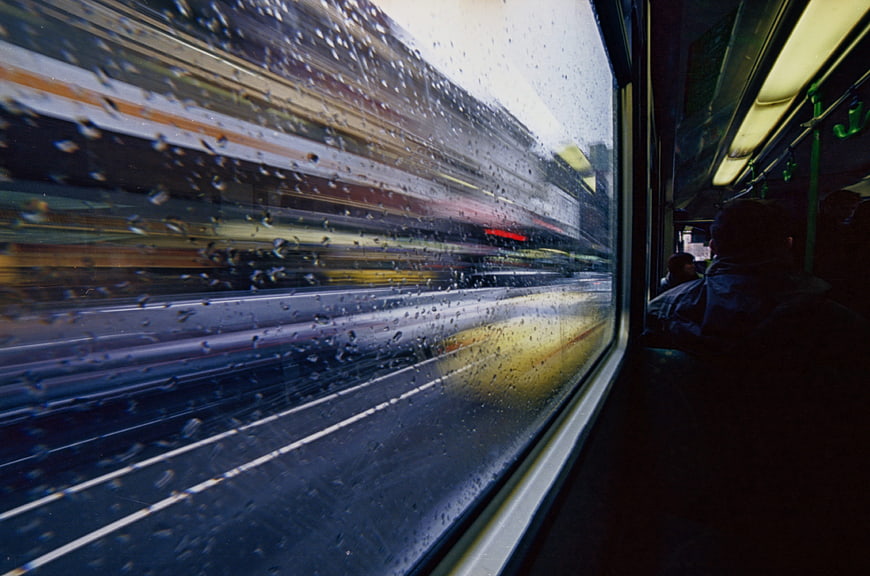 Raindrops on moving tram window with blurred city street view