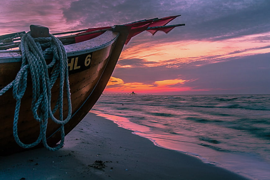 Traditional Wooden Fishing Boat on Beach at Sunset