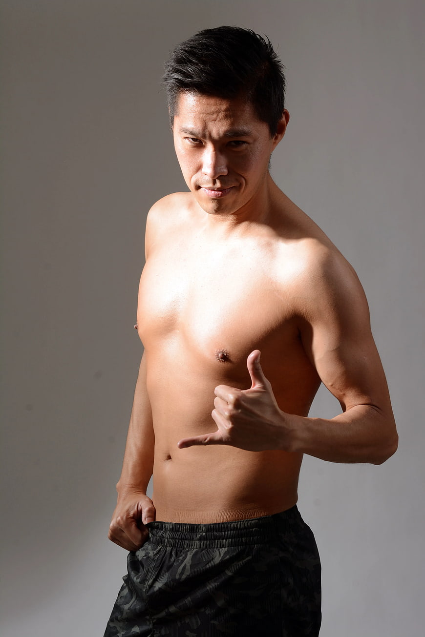 Shirtless Asian Man Making Shaka Sign Against Gray Background