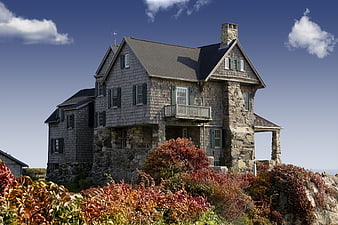 Rustic stone and shingle house on a rocky coastal cliff