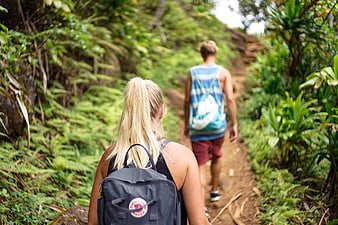 Couple hiking on a lush jungle trail with backpacks