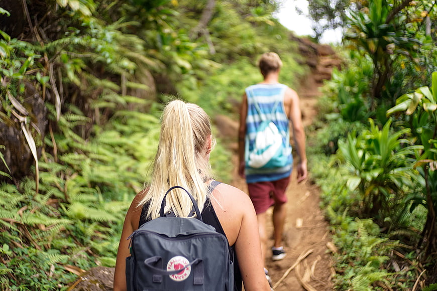 Couple hiking on a lush jungle trail with backpacks