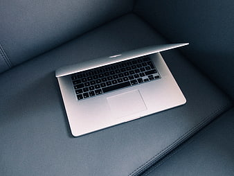 Silver laptop on dark leather sofa