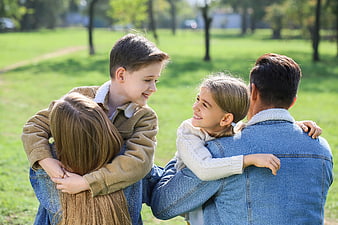 Happy family hugging together in a sunny green park