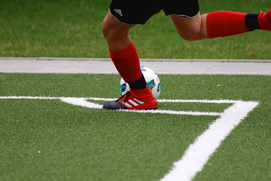 Close-up of soccer player's foot and ball on artificial turf corner