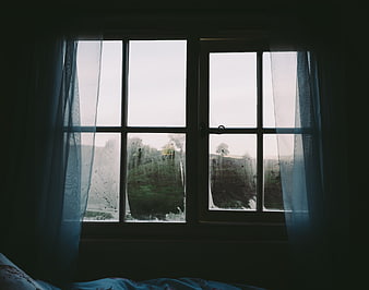 Dark moody bedroom window with rain and green landscape