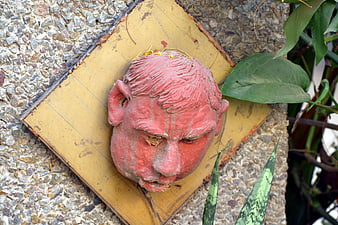 Weathered Red Sculpted Head Mounted on Wall