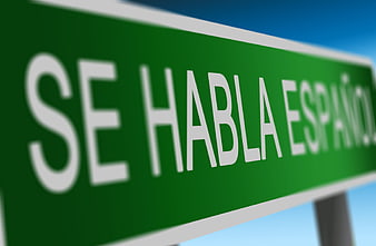 Green Sign Reading Se Habla Español Against Blue Sky