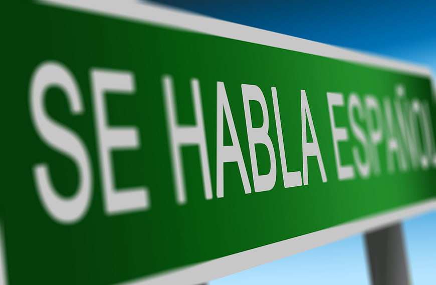 Green Sign Reading Se Habla Español Against Blue Sky