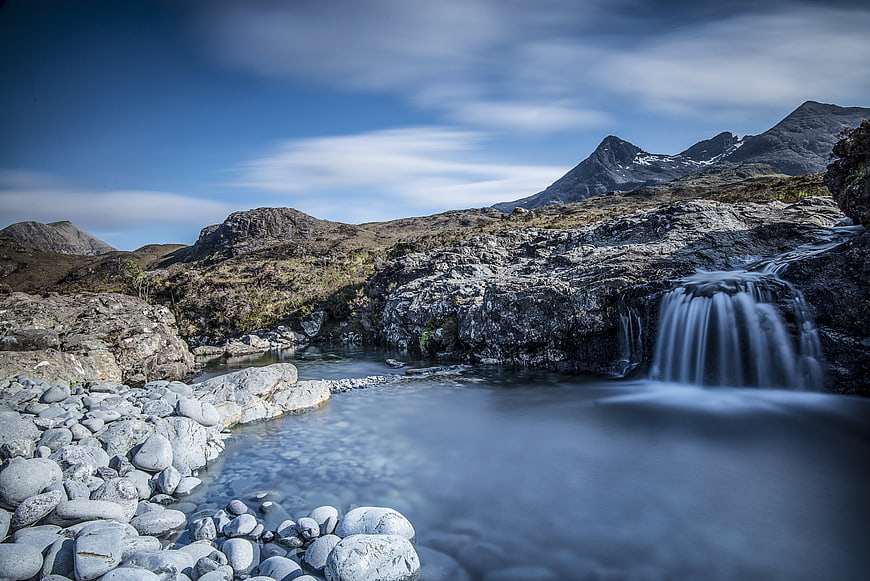 Serene Mountain Stream with Waterfall and Rocky Landscape