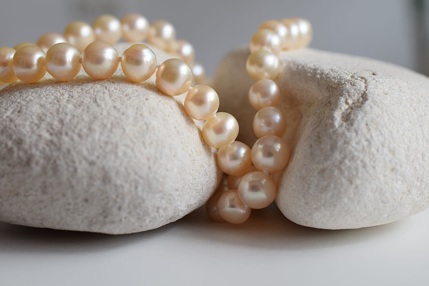 Elegant Cream Pearl Necklace Draped on Smooth White Stones