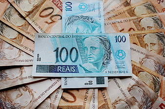 Brazilian 100 Reais banknote on pile of currency