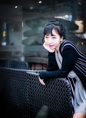 Young Asian Woman Leaning on Wicker Chair Outdoors