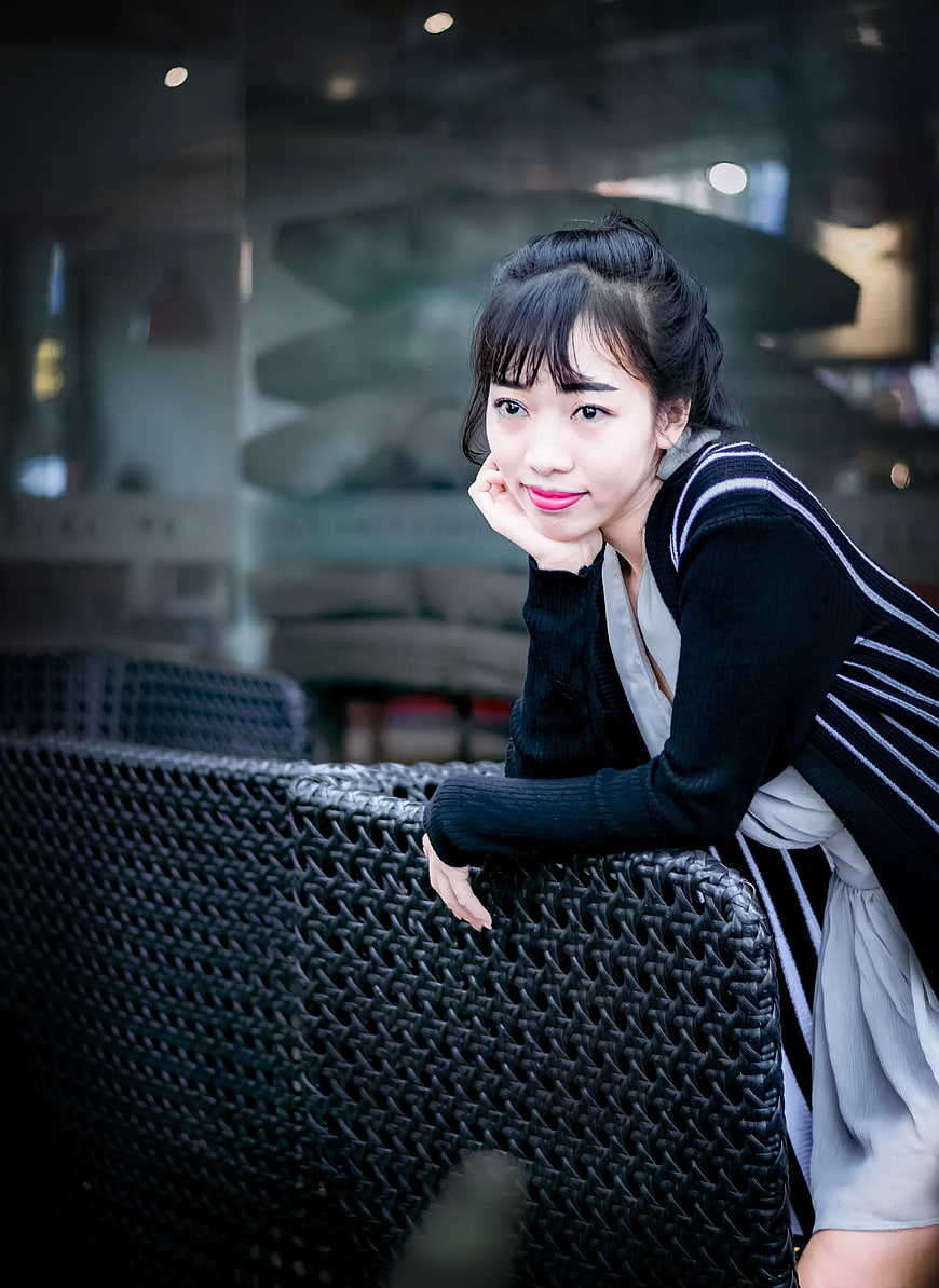 Young Asian Woman Leaning on Wicker Chair Outdoors