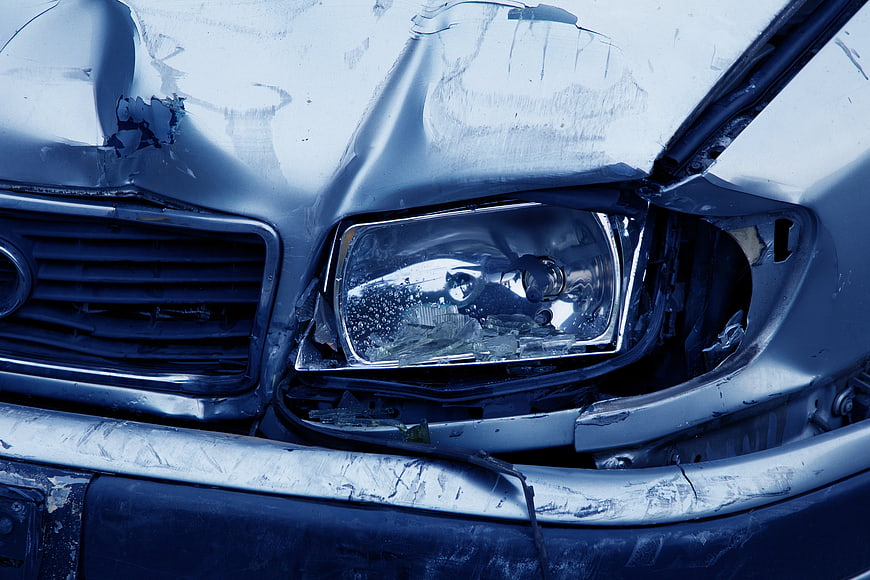 Close-up of damaged car headlight and bumper after accident