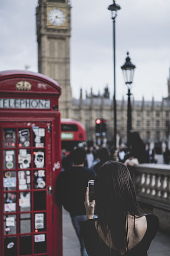 Woman taking photo of Big Ben and red telephone booth in London