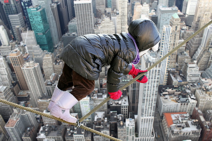 Child Balancing on High Wire Over City Skyline