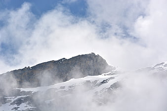 Snowy mountain peak emerging through clouds