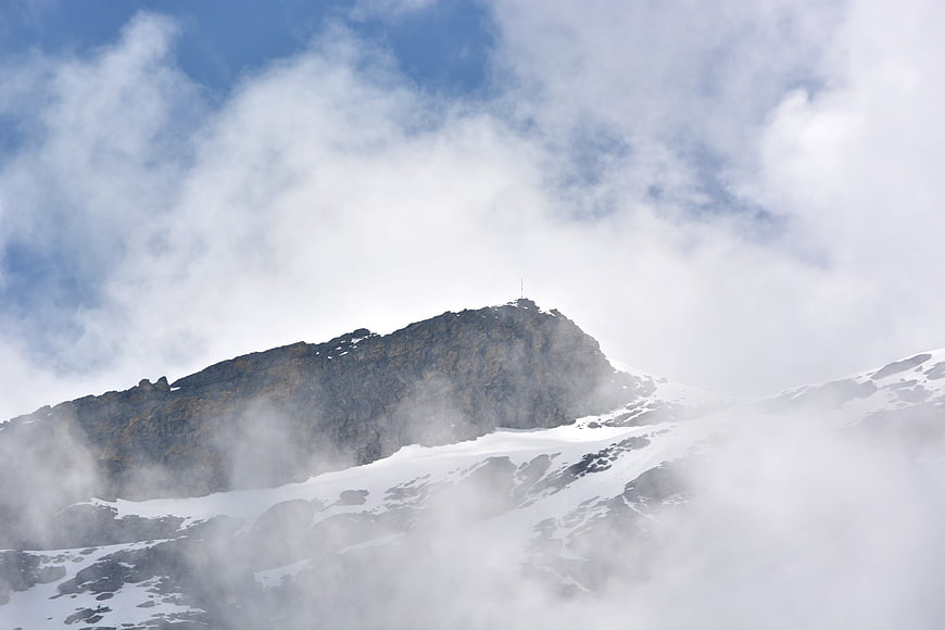 Snowy mountain peak emerging through clouds