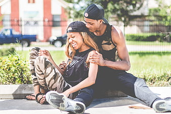 Happy African American Couple Sitting Outdoors On A Sunny Day