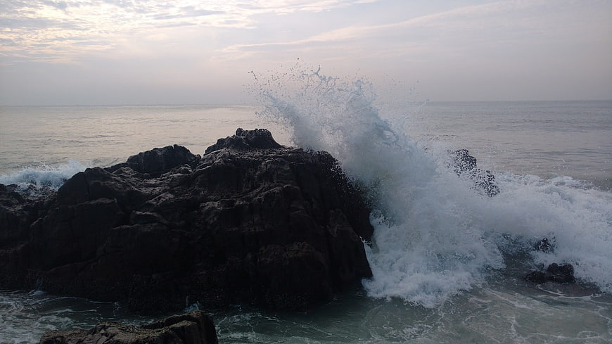 Powerful Ocean Wave Crashing Against Dark Rocky Coastline