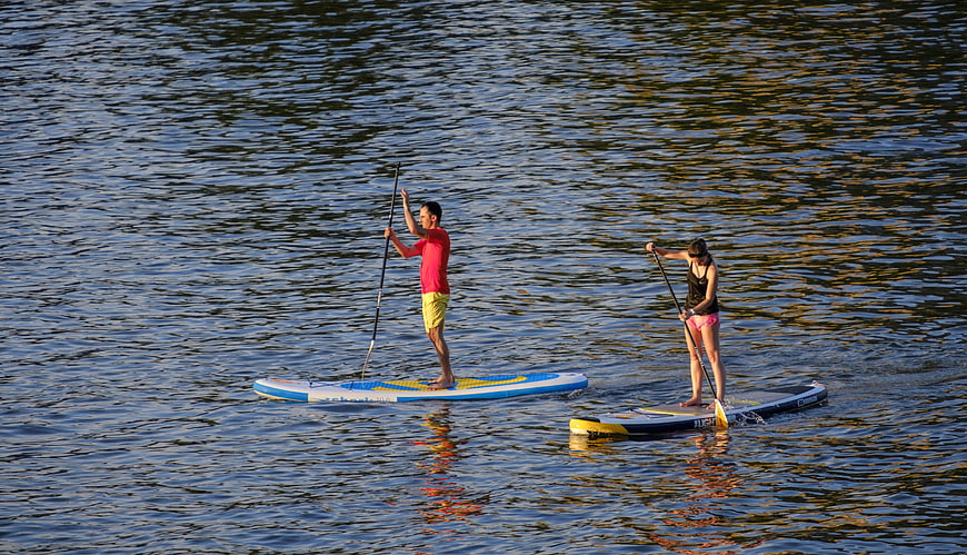 Two People Stand Up Paddling on a Calm Lake at Sunset