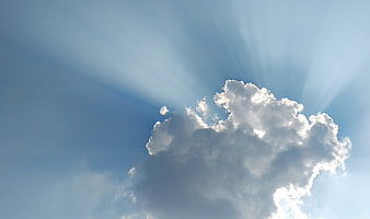 Dramatic Sun Rays Bursting Through Fluffy White Clouds in Blue Sky
